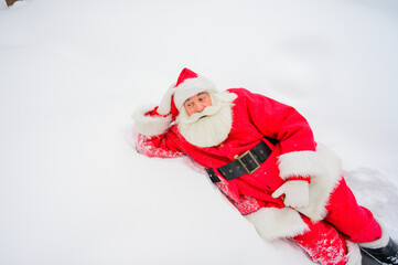 Happy santa claus lying in the snow and fooling around