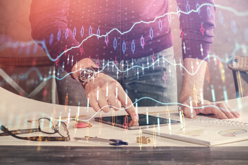 Double exposure of man's hands holding and using a digital device and forex graph drawing. Financial market concept.