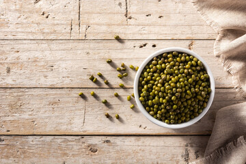 Green soy beans in white bowl on wooden table. Top view. Copy space