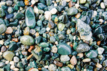 Colorful sea pebbles on the shore close up. Top view, flat lay. Abstract background texture, sea stones in water.