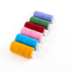 row of colored cotton threads orange blue and lilac on a white isolated background