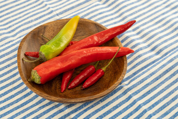 big and small pod of red and green chili peppers in a wooden plate