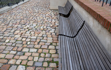 wood-paneled benches by a bright plaster wall in a park sunk with leaves and creepers other clean...