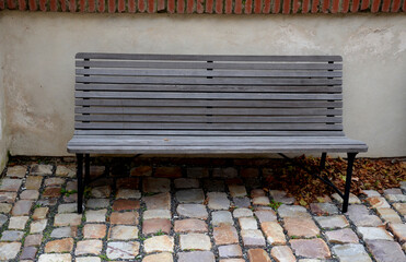 wood-paneled benches by a bright plaster wall in a park sunk with leaves and creepers other clean...