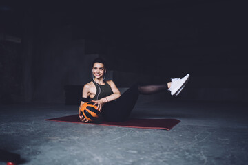 Cheerful woman doing sit ups with weight ball