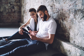 Smiling couple using tablet sitting on floor