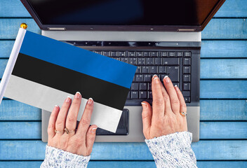 woman hands and flag of Estonia on computer, laptop keyboard 
