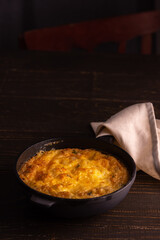 Frittata with cheese, mozzarella and stewed pumpkin in a cast iron pan on a wooden background