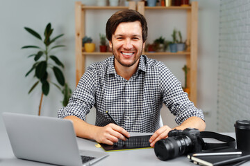 Young man photographer sits at table and works from home