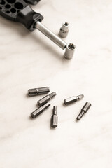 universal engineer hand tool screwdriver and scattering bits on wooden background