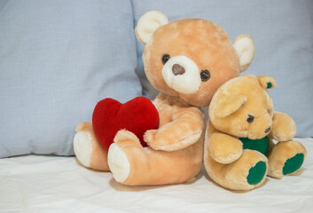 Teddy bears on the bed with a heart-shaped cushion. Valentine's Day concept 2021.