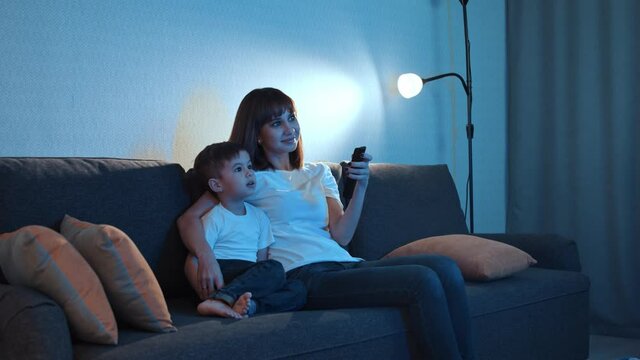 Happy family - mother with her little son sits on the couch and watching TV