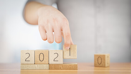 Hand changes the wooden cube from 2020 to 2021. Happy New Year 2021. 3D rendering.