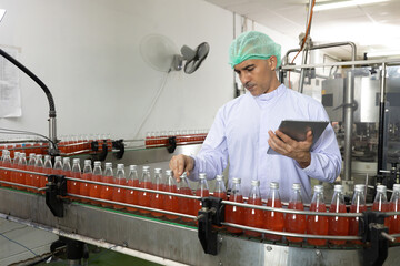 male factory worker looking at basil seed drink for checking quality in beverage factory