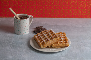 Two homemade waffles with a cup of hot chocolate over a table on christmas.
