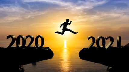 Silhouette man jump between 2020 and 2021 years with sunset background,year 2021 concept