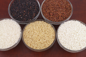 Assortment of rice in glass bowls close up - white, brown, red and black rice.