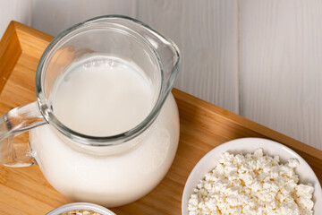 Glass pitcher of milk and bowl of cottage cheese on wooden table