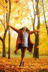 Young black woman throwing autumn leaves in the autumn forest