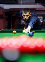 young man lines up his shot as he breaks the balls for start game of billiards