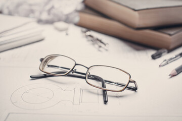 Glasses next to books, compass and pencils