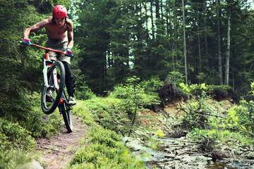 Young male cyclist jumping in the mountain forest of the Carpathian Mountains.