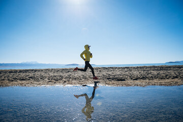 Woman trail runner cross country running on winter high altitude lakeside