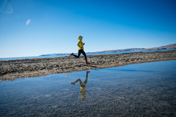 Woman trail runner cross country running on winter high altitude lakeside