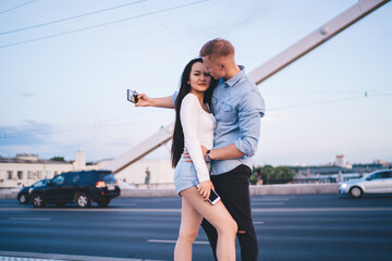 Tender couple taking photo on suspension bridge