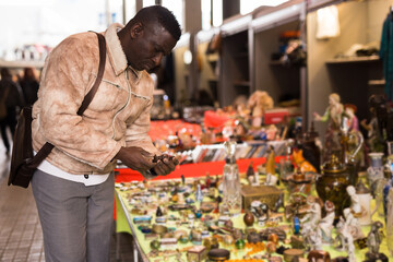 African American man chooses antiques on the flea market