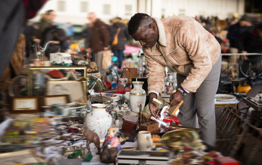 African American man chooses antiques on the flea market