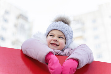 little girl in winter clothes smiles sinisterly. disobedient child. kid manipulator. winter outdoor activities
