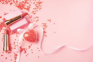 set of lipsticks for makeup on a pink background with a decor in the shape of a heart. Concept of cosmetic products for St Valentines Day