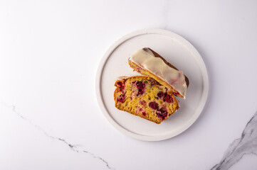 Two pieces of homemade cupcake with cranberries and icing sugar on a white plate on a light background, top view, copy space