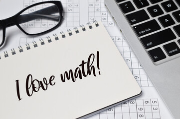 Top angle view of laptop, eyeglasses and notebook written with text I LOVE MATH!. Education concept.