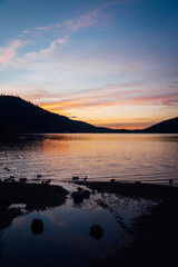 Un coucher de soleil sur le lac de Gérardmer. Un coucher de soleil sur un lac entre des collines. Un coucher de soleil dans les Vosges.