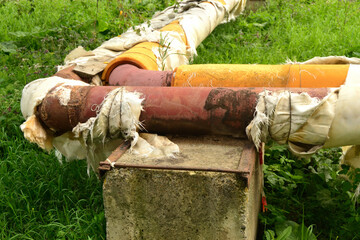 Damaged insulation of a city overhead heating line placed on concrete supports in a residential area of ​​the city. Urban heat supply.