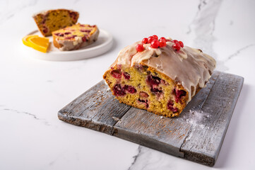 Homemade cupcake with cranberries and icing sugar in the cut and the ingredients on wooden cutting board on light background, copy space