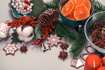 Christmas items with a top view. Pieces of tangerines in a cup, fir twigs, a cone, winter spices,...