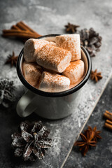 Vintage white metal cup with hot chocolate and marshmallow on the rustic background. Hygge winter evening. Selective focus. Shallow depth of field.