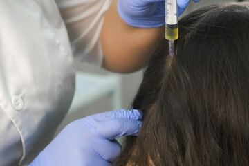 Naklejka premium Doctor trichologist making injections mesotherapy with vitamins in woman skin head for hair growth and against dandruff in cosmetology clinic, closeup view. Hairs cure. Trichology in medicine.