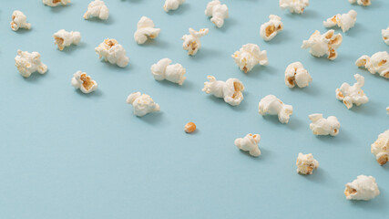 Creative composition made of popcorn and one corn seed on pastel blue background. Minimal diversity concept with copy space. Isometric view.