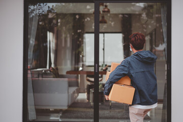 Asian postman with a hygiene protective face mask picking up a parcel package or parcel box from the truck for deliver to customer's door. New Normal concept during covid-19 or coronavirus pandemic