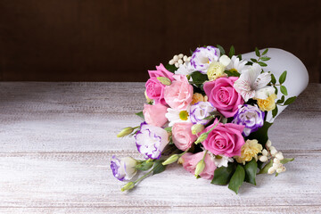 bouquet of roses, daisies, lisianthus, chrysanthemums, unopened buds in a white round box on a wooden table.