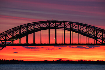 Vibrant sunset colors over a steel tied arch bridge. Fire Island Inlet Bridge, Captree State Park New York