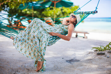 Adorable girl on tropical vacation relaxing in hammock