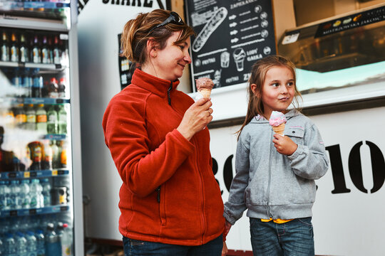 Mother And Her Daughter Eating Ice Cream Sitting On A Step In Front Of Food Truck