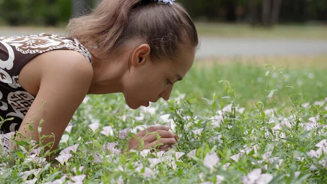 A girl admires flowers in a city park.