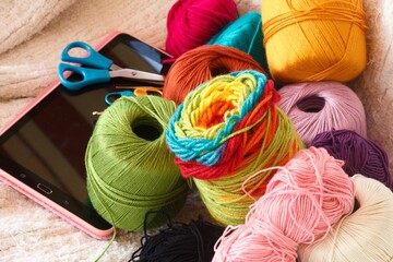 tablet with threads, colored wool and crochet needles for online classes