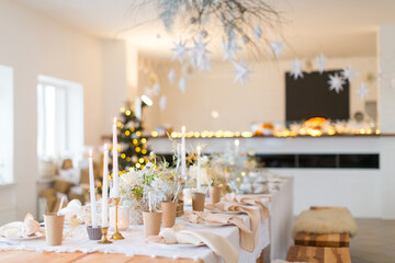 Christmas decoration of the festive table with cakes, glasses and candles